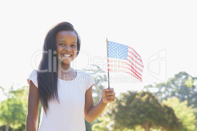 Little girl smiling at camera waving american flag