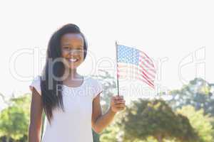 Little girl smiling at camera waving american flag