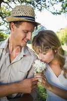Smiling man offering his girlfriend a white flower in the park