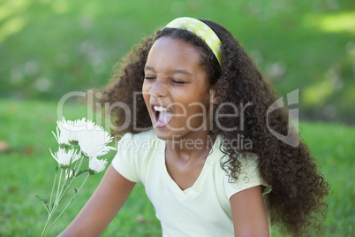 Young girl holding a flower and sneezing in the park