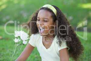 Young girl holding a flower and sneezing in the park