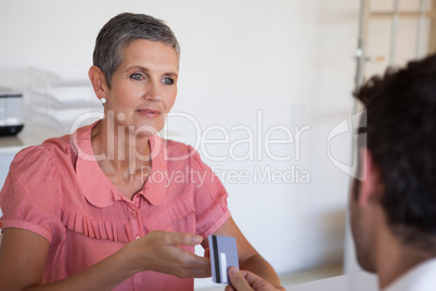 Casual saleswoman taking credit card from customer