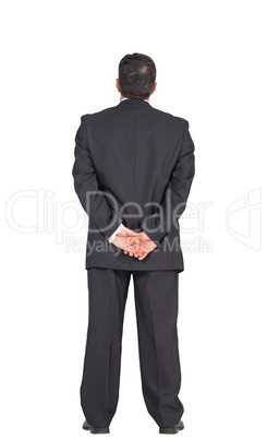 Mature businessman standing with hands behind back