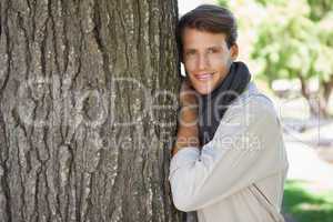 Handsome man leaning against tree smiling at camera