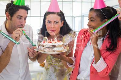 Businesswoman blowing out candles on cake