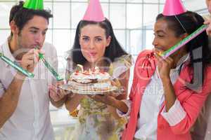 Businesswoman blowing out candles on cake