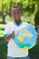 Little boy smiling at camera holding globe in the park