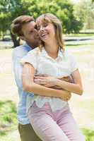 Handsome man picking up his laughing girlfriend in the park