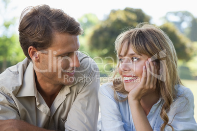 Carefree couple lying in the park smiling at each other
