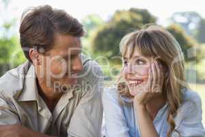 Carefree couple lying in the park smiling at each other