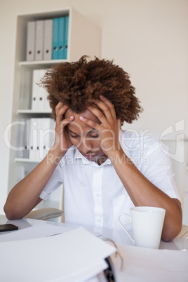 Casual stressed businessman with his head down at desk