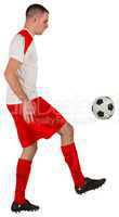 Fit football player playing with ball