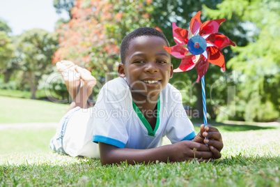 Little boy holding pinwheel in the park smiling at camera