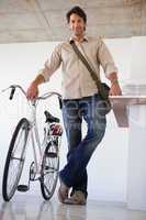 Casual businessman standing with his bike smiling at camera