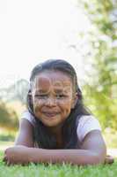 Little girl lying in the park smiling at camera