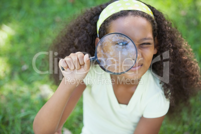 Young girl looking through magnifying glass in the park