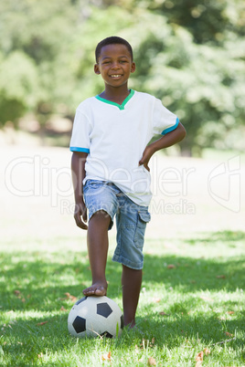 Little boy standing with football in the park
