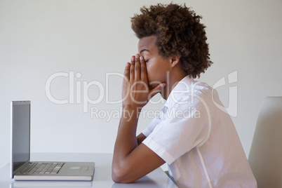 Casual businessman feeling exhausted at his desk