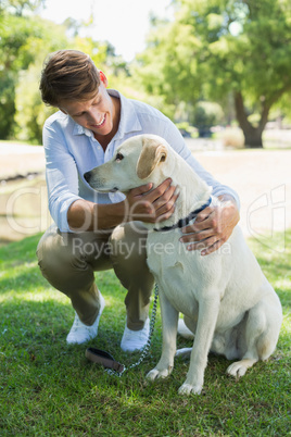 Handsome smiling man with his labrador in the park