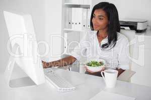 Happy pretty businesswoman eating a salad at her desk