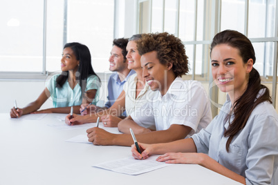 Worker at board meeting smiles to camera