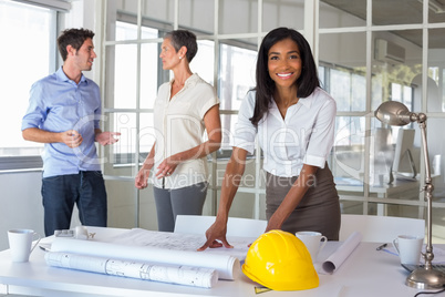 Workers loooking over plans and smiling at camera