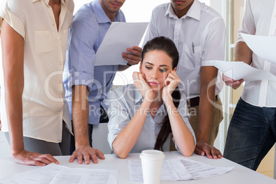 Worried businesswoman surrounded by colleagues