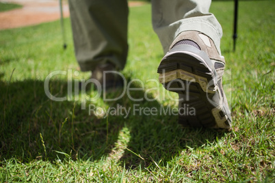 Womans feet in hiking boots walking on grass
