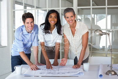 Architects working on blueprints smile to camera