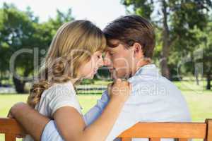 Couple relaxing on park bench together head to head