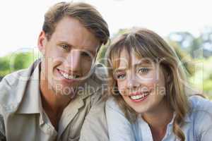 Carefree couple lying in the park smiling at camera