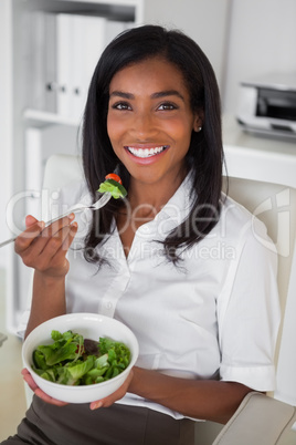 Casual pretty businesswoman eating a salad at her desk