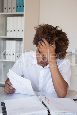 Casual stressed businessman going over paperwork at his desk