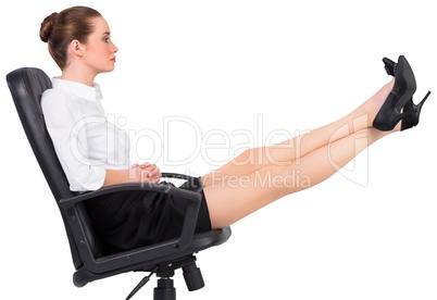Businesswoman sitting on swivel chair with feet up