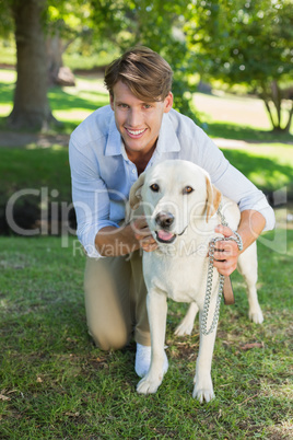 Handsome smiling man posing with his labrador in the park