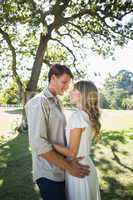 Smiling couple standing and embracing in park