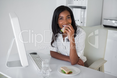 Pretty businesswoman having a sandwich at her desk