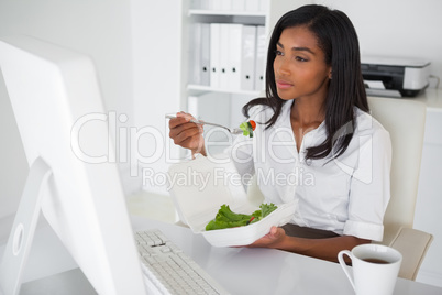 Pretty businesswoman eating a salad at her desk