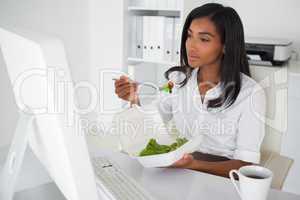 Pretty businesswoman eating a salad at her desk