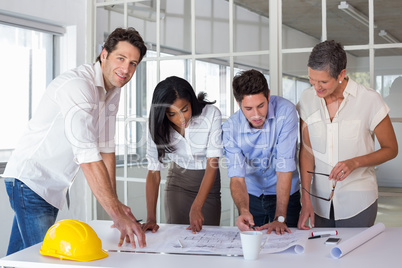 Team of architects going over blueprints with one smiling at cam