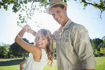 Cute couple dancing in the park smiling at camera