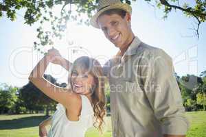 Cute couple dancing in the park smiling at camera