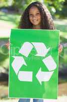 Young environmental activist smiling at the camera holding a pos