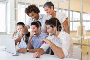 Workers laugh while looking at laptop