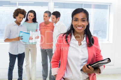 Attractive worker with planner smiles at camera with colleagues