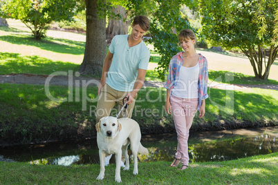 Happy couple walking with their labrador in the park