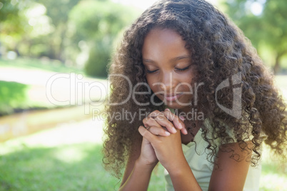 Young girl praying in the park