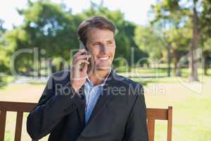 Casual businessman talking on phone on park bench