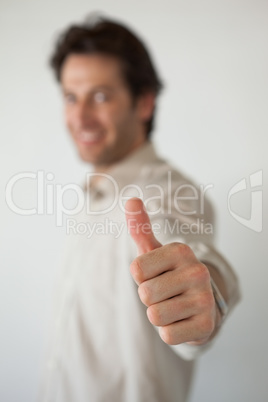 Casual smiling businessman showing thumbs up to camera