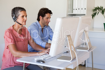 Casual business team working at desk using computers with woman